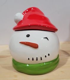 a ceramic snowman with a red hat on it's head