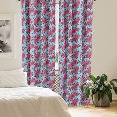 a bed room with a neatly made bed and a window covered in pink and blue curtains