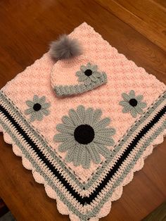 a crocheted blanket and hat are on a table