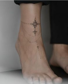 a woman's foot with a cross tattoo on the bottom of her left ankle