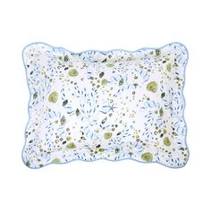 a white pillow with blue trim and green leaves on the front, sitting on a white surface