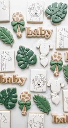 baby cookies decorated with green and white icing are arranged on a table in the shape of jungle animals