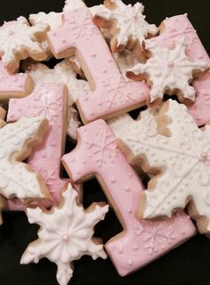 some pink and white decorated cookies in the shape of letter t with snowflakes on them