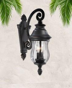 an outdoor wall light with two lights on it and palm tree branches in the background