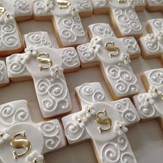 decorated cookies are arranged in the shape of cross and letteres, with gold accents