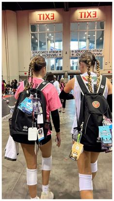 two girls with back packs and knee pads walking through an airport terminal, both carrying backpacks on their backs