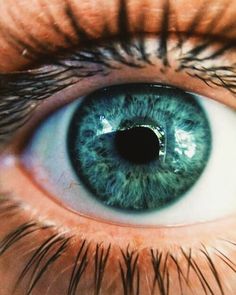 an eye with blue and green iris looking at the camera, close up photo taken from below