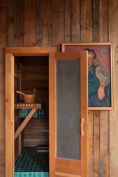 a painting is hanging on the wall next to a sauna in a wooden room