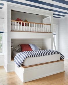 a white bunk bed sitting under a blue and white striped ceiling in a bedroom next to a window