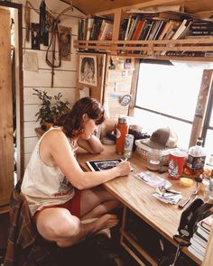 a woman sitting at a desk in front of a window with books on the shelves