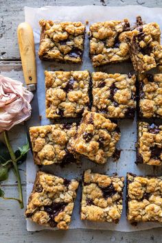 chocolate chip cookie bars cut into squares and placed on parchment paper next to a pink rose