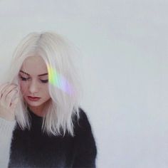 a woman with white hair is looking down at her cell phone while wearing a black sweater