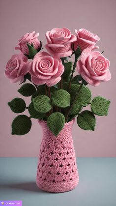 a crocheted vase with pink roses in it and green leaves on the bottom