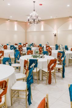 a banquet hall with tables and chairs set up for an event or function, decorated in blue and orange