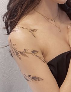 a woman with a tattoo on her shoulder and chest is looking at the camera while wearing a black dress