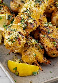 chicken wings with lemon wedges and parsley on a baking sheet