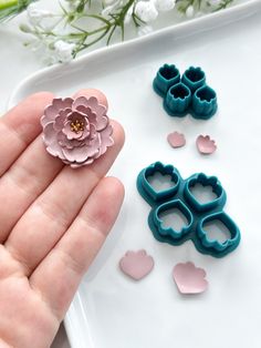 a person holding some fake flowers in their hand next to hearts and cookie cutters