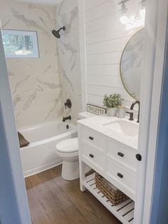 a bathroom with a toilet, sink and bathtub next to a mirror on the wall