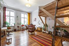 a living room filled with furniture and wooden flooring next to two large open windows