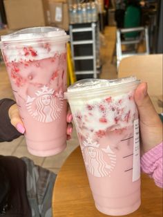 two pink starbucks drinks are sitting on a table