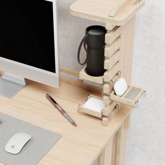 a computer monitor, keyboard and mouse on a wooden desk with a black coffee mug