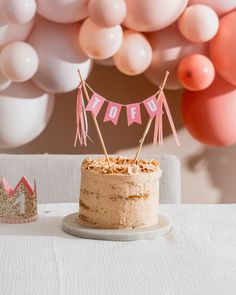 a birthday cake sitting on top of a table next to pink and white balloon decorations