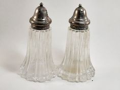 two glass salt and pepper shakers on a white background