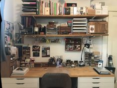 an office desk with lots of books and papers on top of it, along with a chair