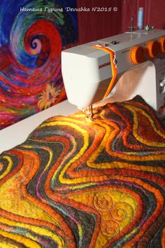 a sewing machine sitting on top of a table next to a colorful wallpaper covered in swirls