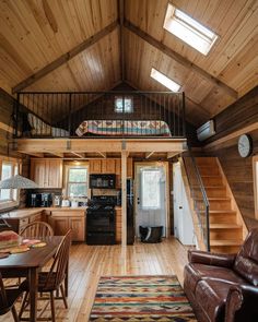 a living room and dining area in a small cabin with wood flooring, wooden walls and ceiling