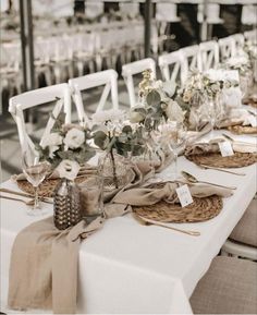 the table is set with white chairs and place settings for guests to sit down at