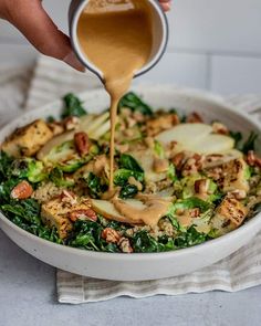 a person pouring dressing into a bowl filled with vegetables and other ingredients to make the dish