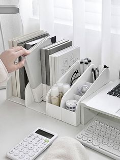 a white desk with a laptop, keyboard and various office supplies on top of it