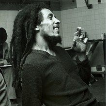 a black and white photo of a man with dreadlocks