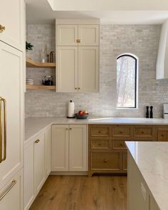 a kitchen with white cabinets and wood floors