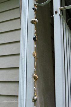 a window sill hanging from the side of a house with beads and chains attached to it