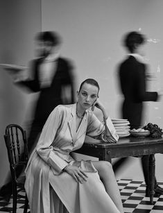 a black and white photo of a woman sitting at a table