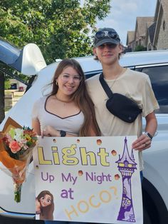 two people standing next to each other holding a sign that says light up my night at hoco