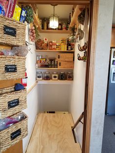 an open pantry with baskets and food items on shelves next to a door that leads to the kitchen