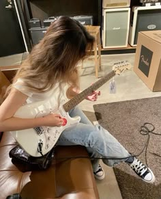 a woman sitting on top of a couch playing an electric guitar