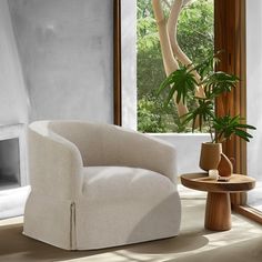 a white chair sitting in front of a window next to a potted plant