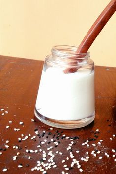 a jar filled with white and brown sugar sitting on top of a wooden table next to a spoon