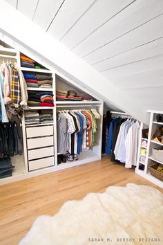 an attic closet with white shelving and drawers