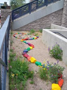 there are many colorful rocks on the ground in this garden, along with plants and flowers