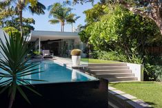 the pool is surrounded by palm trees and greenery, with stairs leading up to it