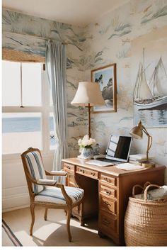 a desk with a laptop computer on top of it next to a lamp and window