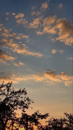 the sun is setting behind some trees