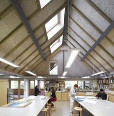 people are sitting at desks in a large room with vaulted ceilings and open bookshelves