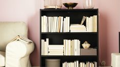 a bookshelf filled with lots of books next to a white chair