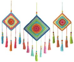 three colorful wall hangings with tassels on them